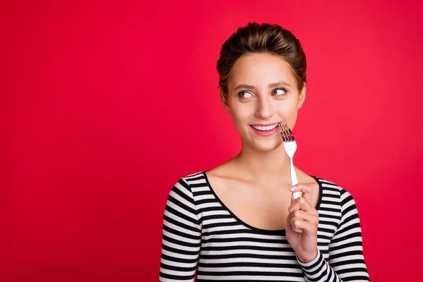 Photo de douce charmante jeune femme porter des vêtements rayés lécher fourchette à la recherche d'espace vide sourire isolé fond de couleur rouge — Photo