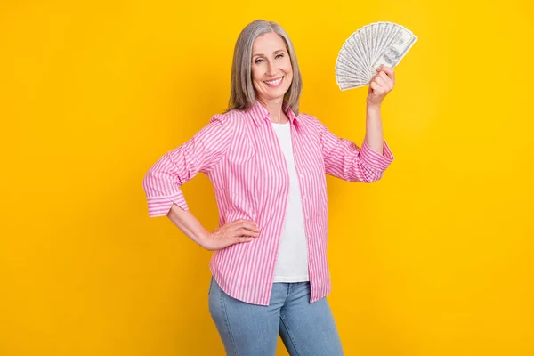 Profil boční fotografie staré ženy šťastný pozitivní úsměv bohatý hold peníze peníze izolované přes žlutou barvu pozadí — Stock fotografie