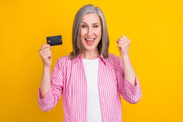 Foto von gealterten Frau glücklich positives Lächeln freuen Sieg Erfolg Gewinn halten Bankkarte isoliert über gelben Hintergrund — Stockfoto