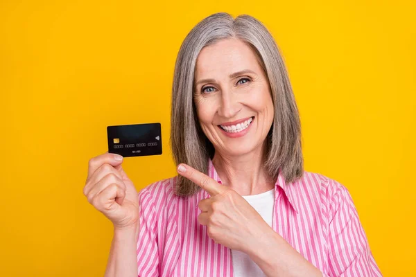 Foto da mulher idosa feliz sorriso positivo ponto dedo banco cartão anúncios aconselhar sugerem isolado sobre fundo de cor amarela — Fotografia de Stock