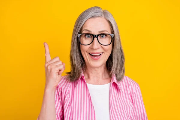 Porträtt av attraktiv glad intelligent gråhårig kvinna pekar pekfinger upp isolerad över ljust gul färg bakgrund — Stockfoto