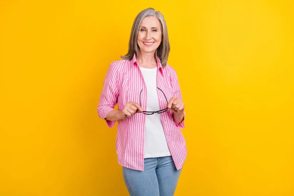 Portret van aantrekkelijke vrolijke wijze slimme slimme grijs-harige vrouw houden in handen specs geïsoleerd over helder gele kleur achtergrond — Stockfoto