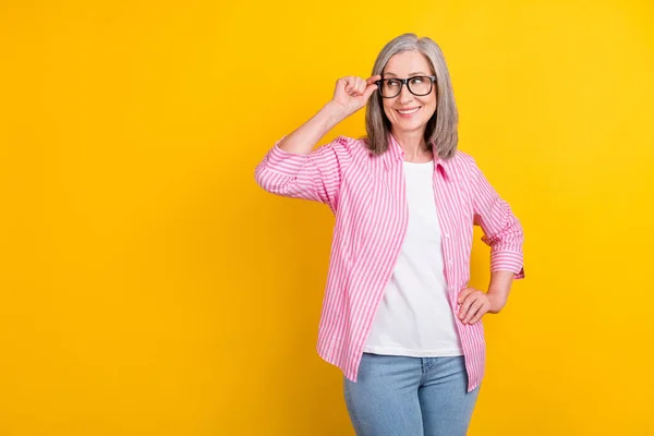 Foto van oude vrouw gelukkig positieve glimlach hand aanraking bril kijken leeg ruimte geïsoleerd over gele kleur achtergrond — Stockfoto