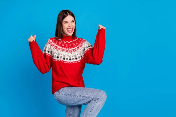 Zdjęcie portret kobieta gestykulując jak zwycięzca w swetrze xmas patrząc copyspace overjoyed odizolowany żywy niebieski kolor tła — Zdjęcie stockowe