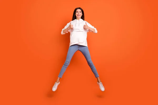 Повнометражний вигляд тіла привабливої веселої дівчини, що стрибає з мініатюрою ізольовано на яскраво-помаранчевому кольоровому фоні — стокове фото