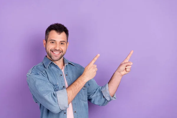 Foto des jungen Mannes glücklich positives Lächeln zeigen Finger leeren Raum direkten Weg folgen Anzeige isoliert über violetten Farbhintergrund — Stockfoto