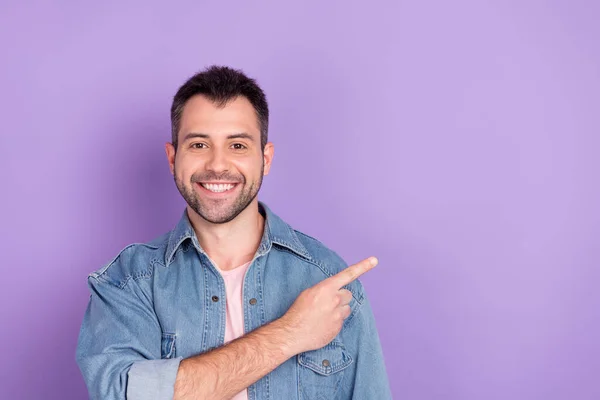 Fénykép a fiatal férfi boldog pozitív mosoly mutatóujj üres tér hirdetési tanácsok választás sugallják elszigetelt felett lila színű háttér — Stock Fotó