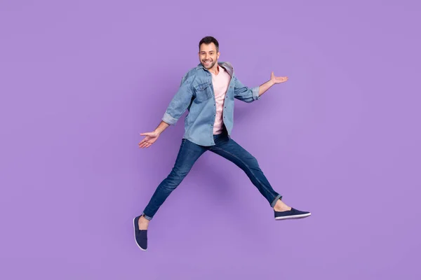 Фотография мужчины в полный рост, улыбающегося, прыгающего на высоком веселом фоне фиолетового цвета — стоковое фото