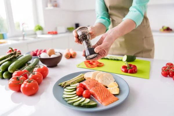 Ritagliato foto di casalinga signora mani cucinare colazione dieta tenere pepe scatola spezie cibo indossare grembiule cucina stanza al chiuso — Foto Stock