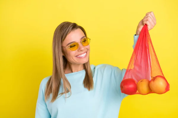 Retrato de menina alegre moda atraente segurando saco com frutas frescas isoladas sobre fundo de cor amarela brilhante — Fotografia de Stock