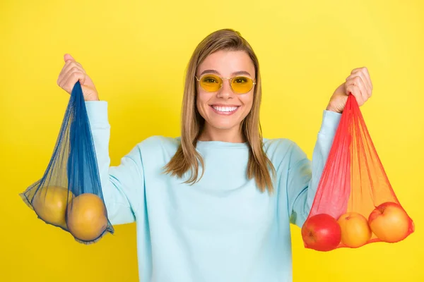 Portret atrakcyjnej wesołej dziewczyny trzymającej torby z jabłkami organiczne menu dieta izolowana na żywym żółtym tle — Zdjęcie stockowe