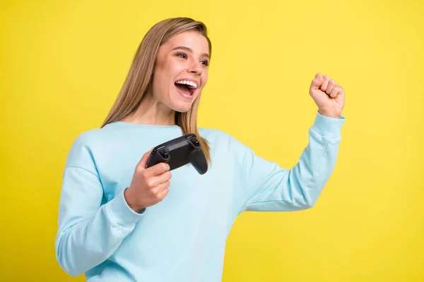 Foto der erstaunten Gewinnerin Dame halten Gamepad heben Faust offenen Mund tragen blauen Pullover isoliert auf gelbem Hintergrund — Stockfoto