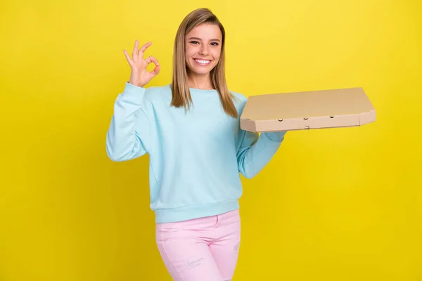 Portret atrakcyjnej wesołej dziewczyny trzymającej zamówienie smaczne pizzy pokazując ok-znak reklamy izolowane na jasnożółtym tle koloru — Zdjęcie stockowe