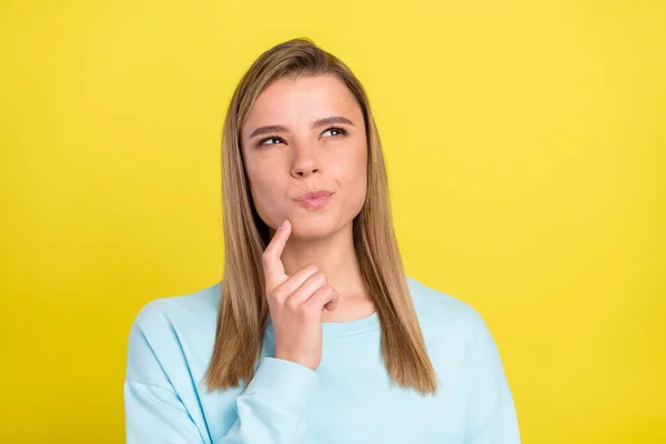 Bild av sinnade smart pensiv flicka finger haka slå upp tomt utrymme bära blå pullover isolerad på gul bakgrund — Stockfoto