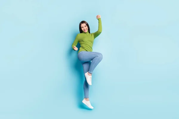 Photo of astonished funky lady jump celebrate victory wear green turtleneck isolated on blue background