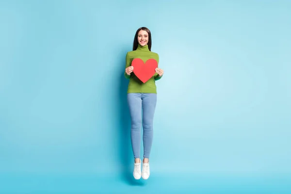 Foto van grappige liefdevolle dame spring hold rood papier hart kaart dragen groen coltrui geïsoleerd op blauwe achtergrond — Stockfoto