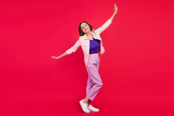Foto von positiven froh Dame strahlend Lächeln fliegen Hände Flügel tragen rosa Jacke isoliert rote Farbe Hintergrund — Stockfoto