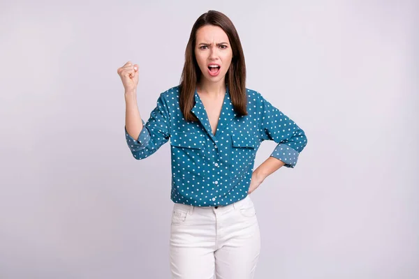 Foto de mujer joven agresiva enojada vestida blusa azul gritando puño creciente aislado color gris fondo —  Fotos de Stock