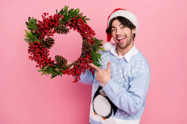 Foto di attraente impressionato giovane uomo vestito blu pullover di Natale puntando dito corona sorridente isolato colore rosa sfondo — Foto Stock