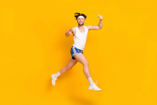 Longitud completa tamaño del cuerpo vista de chico alegre atractivo saltando mostrando pulgar aislado sobre fondo de color amarillo brillante —  Fotos de Stock