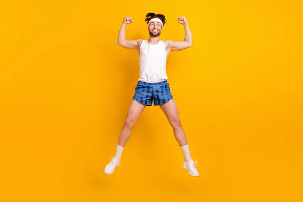 Longitud completa vista del tamaño del cuerpo de chico alegre atractivo saltando divertirse mostrando los músculos aislados sobre fondo de color amarillo brillante —  Fotos de Stock
