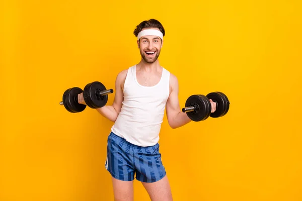 Porträt eines attraktiven, fröhlichen, sportlichen Kerls, der Gewicht hebt und körperliche Arbeit isoliert über einem leuchtend gelben Hintergrund verrichtet — Stockfoto