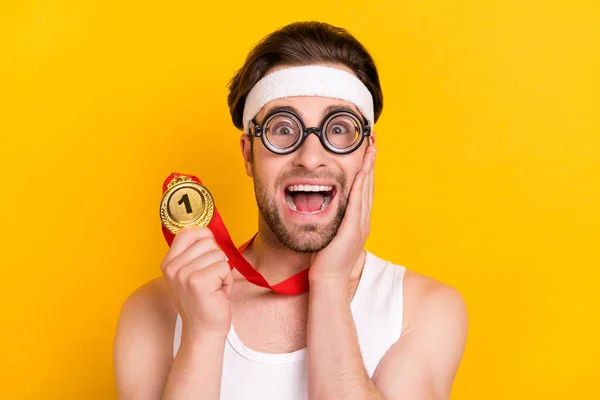 Porträt von gut aussehenden fröhlichen Kerl Nerd Führer hält goldene Medaille großen Erfolg isoliert über leuchtend gelben Farbhintergrund — Stockfoto