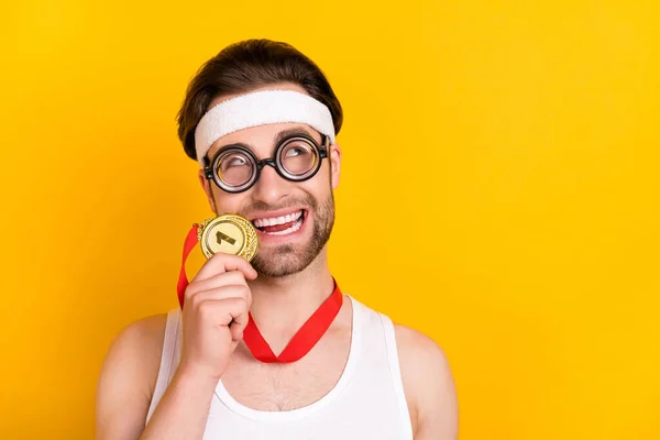 Porträt des gut aussehenden fröhlichen Kerl Nerd Führer hält beißende Medaille Kopierraum isoliert über leuchtend gelben Farbhintergrund — Stockfoto