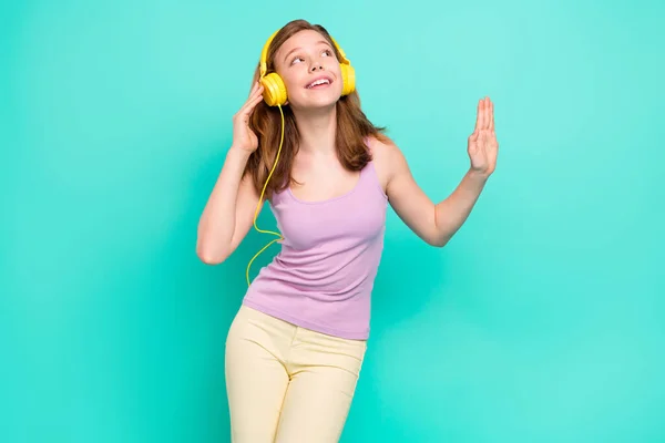 Fotografie pěkné hnědé malé dívky poslouchat hudbu nosit top kalhoty izolované na pozadí teal barva — Stock fotografie