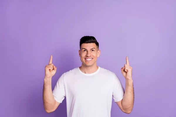 Φωτογραφία του νεαρού άντρα ευτυχής θετική ματιά χαμόγελο δείχνουν δάχτυλα κενό χώρο προτείνει διαφήμιση promo απομονώνονται πάνω από μωβ φόντο χρώμα — Φωτογραφία Αρχείου
