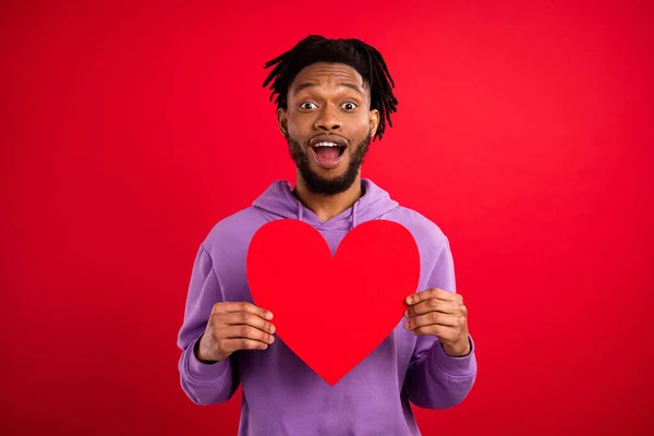 Retrato de atractivo admirador de chico alegre asombrado sosteniendo el signo del corazón que se divierte aislado sobre fondo de color rojo brillante — Foto de Stock