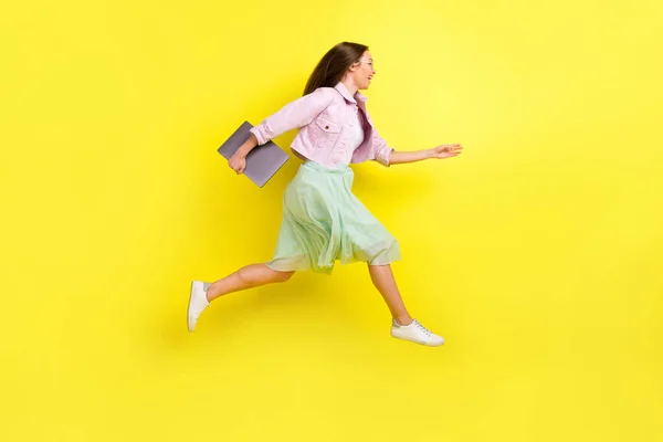 Comprimento total tamanho do corpo foto retrato menina na saia correndo rápido na reunião mantendo laptop isolado cor amarela brilhante fundo — Fotografia de Stock