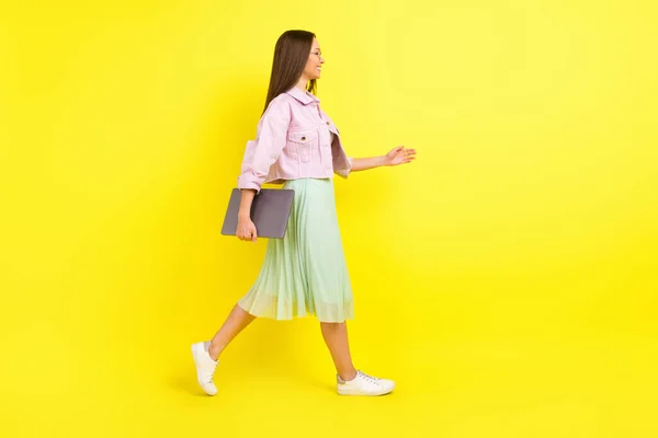 Πλήρης φωτογραφία προφίλ του σώματος του ωραία μελαχρινή hairdo νεαρή κοπέλα πάει με φορητό υπολογιστή φορούν γυαλιά ροζ φούστα πουκάμισο απομονώνονται σε κίτρινο χρώμα φόντο — Φωτογραφία Αρχείου