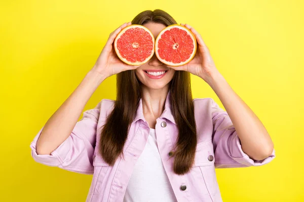Фотопортрет молодої жінки, що прикриває очі двома півтонами грейпфрута, грайливий ізольований яскраво-жовтий кольоровий фон — стокове фото