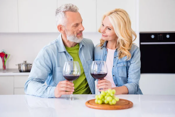 Foto de buen humor positivo sonriente pareja casada de ensueño tienen fecha en casa beber vino comer aperitivo uva — Foto de Stock