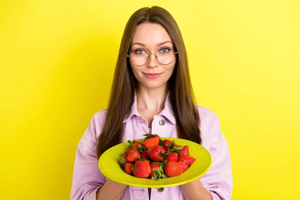 노란 빛깔의 선명 한 배경에 웃고 있는 딸기로 접시를 지키고 있는 젊은 여자 사진 — 스톡 사진