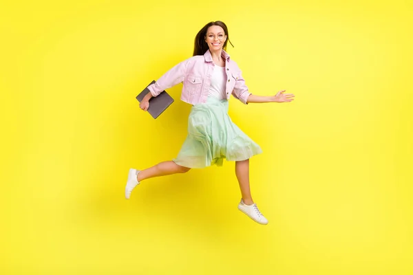 Full length body size view of attractive cheerful girl jumping carrying laptop isolated over bright yellow color background — Stock Photo, Image