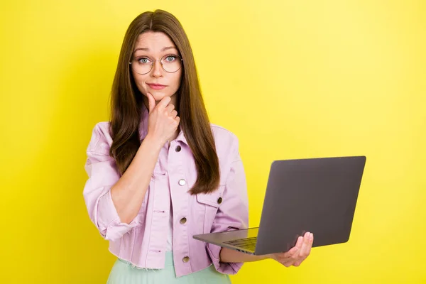 Retrato de chica desconcertada mente atractiva usando ordenador portátil decidir aislado sobre fondo de color amarillo brillante —  Fotos de Stock