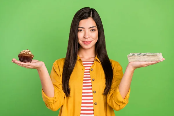 Foto av en ung dame med søt brunette som har pene penger. Gult skjorte isolert på pastellgrønn bakgrunn. – stockfoto