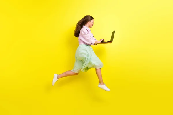 Comprimento total tamanho do corpo foto retrato menina na saia saltando alto trabalhando no computador isolado cor amarela brilhante fundo — Fotografia de Stock