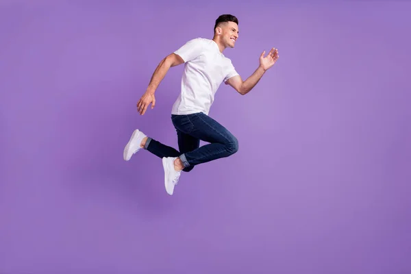 Perfil de comprimento total foto lateral do jovem feliz salto sorriso positivo ir correr rápido isolado sobre fundo cor violeta — Fotografia de Stock