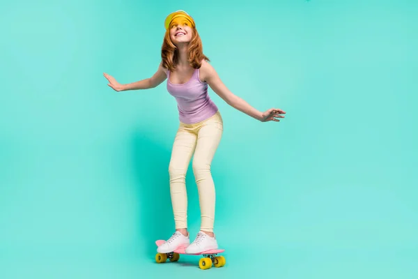 Foto de tamaño completo de la divertida chica adolescente rubia ir a patinar usar pantalones de la tapa superior aislados en color verde azulado fondo — Foto de Stock