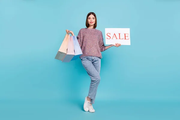 Фото покупця леді тримає угоди з продажу листівки носити в'язані светри джинси взуття ізольовані синій колір фону — стокове фото
