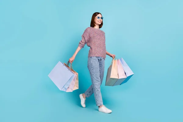 Foto de perfil de senhora bonito andar transportar sacos de varejo usar sapatos de calça de camisola de vidro solar isolado fundo de cor azul — Fotografia de Stock