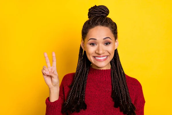 Foto de encantadora divertida señora de piel oscura usar jersey rojo sonriendo mostrando v-signo aislado de color amarillo de fondo —  Fotos de Stock