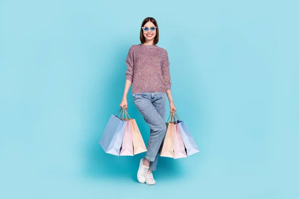 Фото шопоголічної леді тримає пакет магазинів носити сонцезахисні светри джинси взуття ізольовані синій колір фону — стокове фото