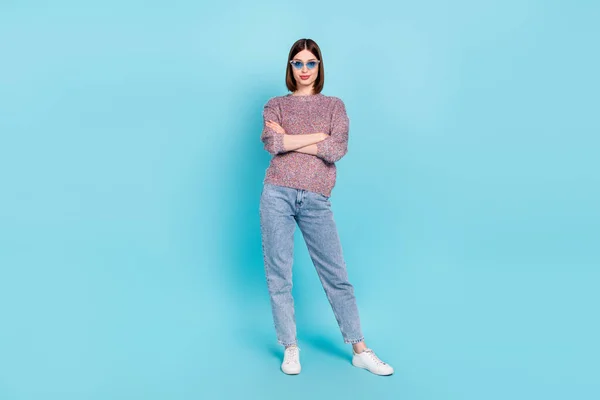 팔을 접힌 여성의 사진에는 선글라스에 뜨개 질을 한 풀잎진 바지를 입고 있으며, 격리 된 파란색 배경 신발을 신고 있다 — 스톡 사진