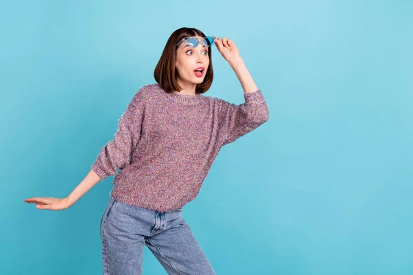Photo of amazed funky lady look empty space open mouth wear sunglass knitted sweater isolated blue color background — Stock Photo, Image
