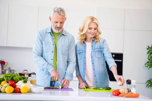 Foto av bedårande söt åldrade par bära denim skjorta ler matlagning färsk sallad inomhus hus rum — Stockfoto