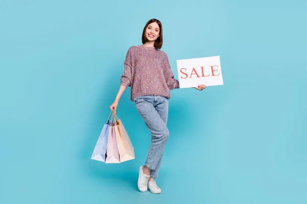 Fénykép a vidám hölgy vásárolni ruhák csomagok hold eladó kártya viselet pulóver farmer cipő elszigetelt kék szín háttér — Stock Fotó